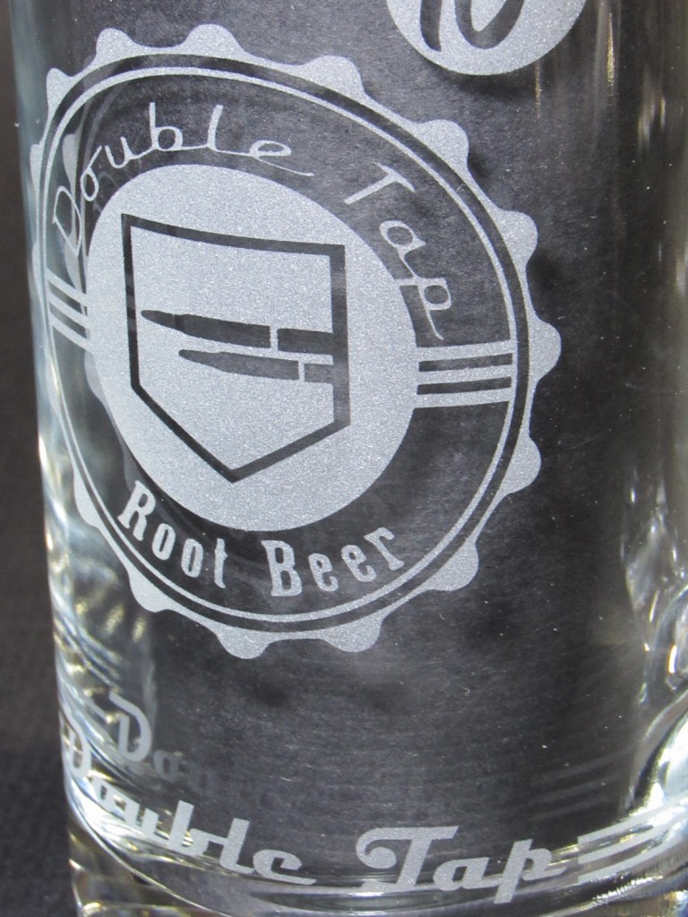 A close-up left 3/4 view of the mug featuring the Double Tap logo and text reading "Double Tap" with stripes near the bottom.